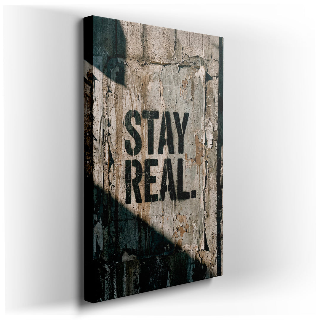 Urban wall art featuring 'Stay Real' in black graffiti-style font on a distressed, textured background with shadows.